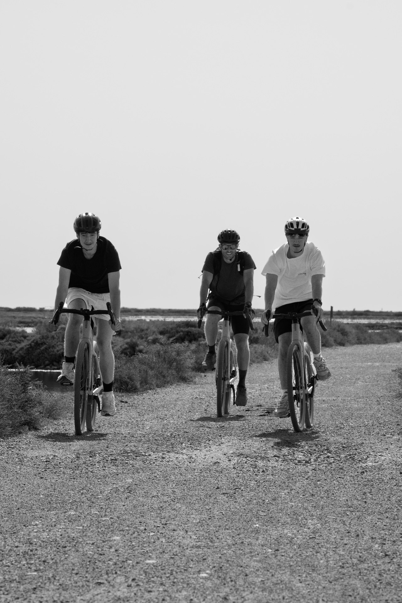 Three cyclists riding away on the gravel trail, Gruissan