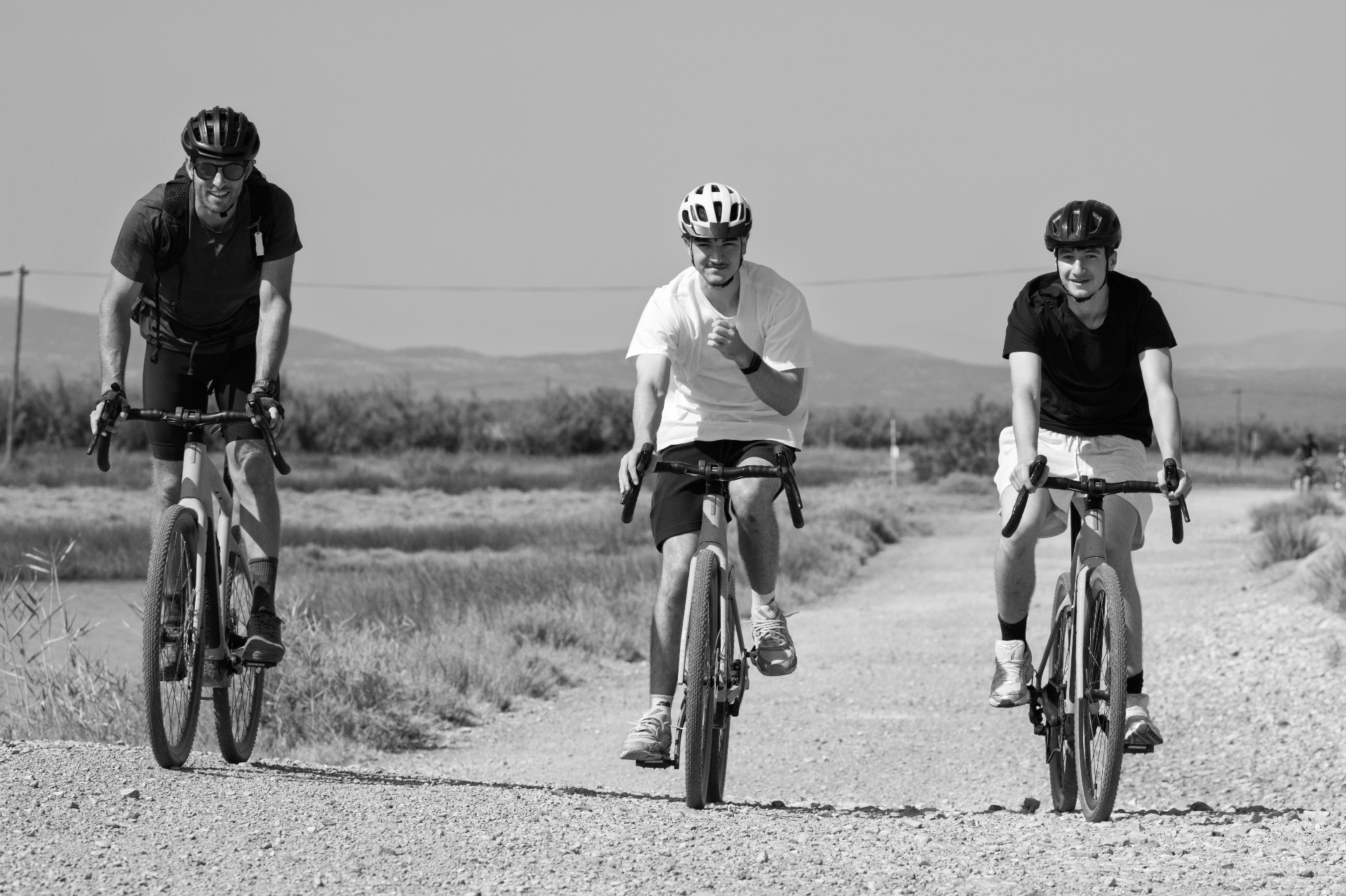 Three cyclists riding toward the camera on a gravel path, Gruissan